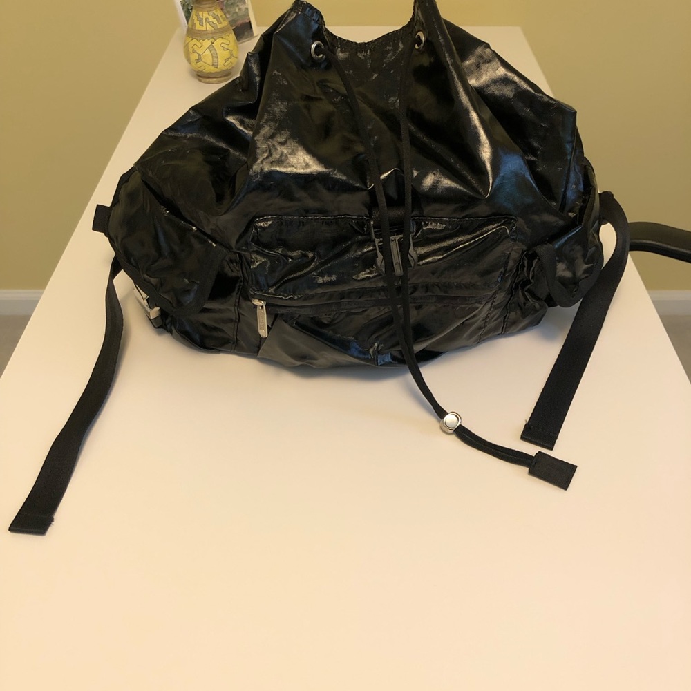 A large black shiny Sportsac backpack with many pockets/zippers inside and out.